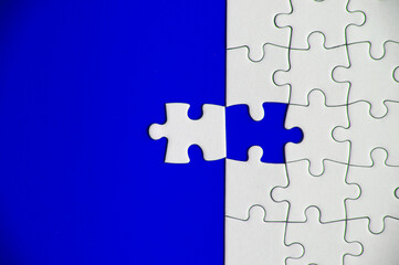 Fototapeta premium Top view of missing jigsaw puzzle on blue cover background. Copy space