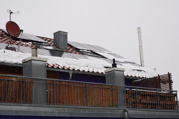 Photovoltaik im Winter. Die Panels sind teilweise mit Schnee bedeckt und weiterer Schnee fällt