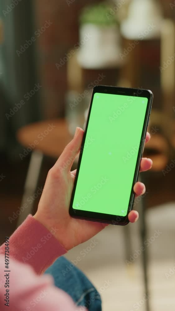 Aufkleber Vertical Screen: Feminine Hand Scrolling Feed on Smartphone with Green Screen Mock Up Display. Female Resting at Home and Checking Social Media on Mobile Device. Close Up Over the Shoulder Footage.