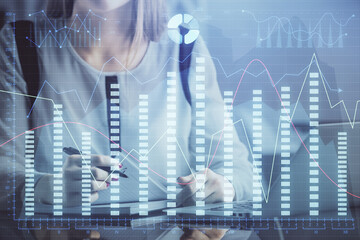 Double exposure of businesswoman hands typing on computer and financial graph hologram drawing. Stock market analysis concept.