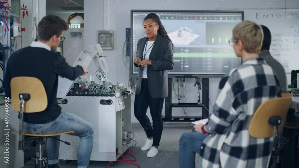 Poster teacher holding lesson to diverse students while showing at robotic hand and at big screen in univer