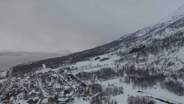Olderdalen town nestled at foot of mountain, freezing snowy landscape; aerial