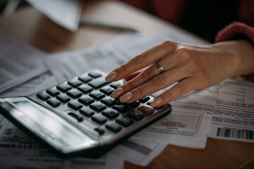 Close-up female hands with a calculator and abacus in the living room at home. A young woman calculates monthly household expenses