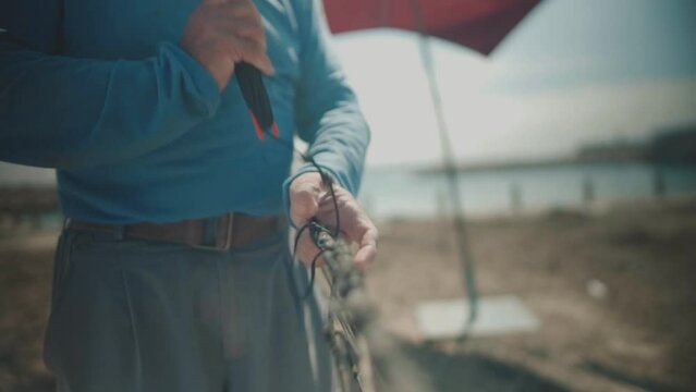 Fisherman repairing fishing net at beach, cinematic shot
