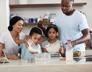Spending some quality time in the kitchen. Cropped shot of a young family baking together in the...