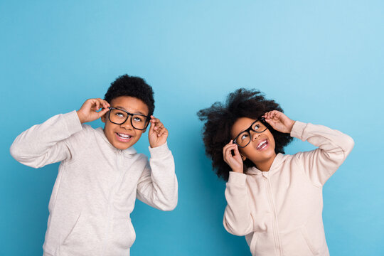 Portrait of attractive cheerful schoolchildren thinking touching specs isolated over bright blue color background