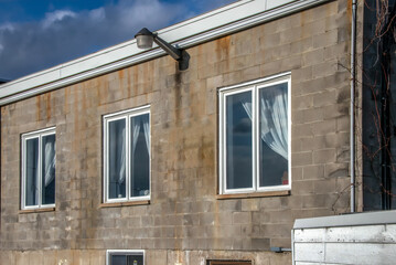 Daytime facade of a concrete block construction, flat roof building, windows with curtains, nobody