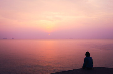 Woman on holiday, looking to sea with beautiful view in the evening. Sunset at the island, romantic background concept.