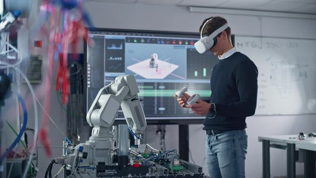 Male Student in VR Googles Lifting and Moving Bionic Hand wit Controllers while Doing his Project at the University. Computer Science and Education Concept