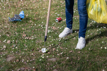 Close up of man collecting garbage with stick as a tool in the park with flowers