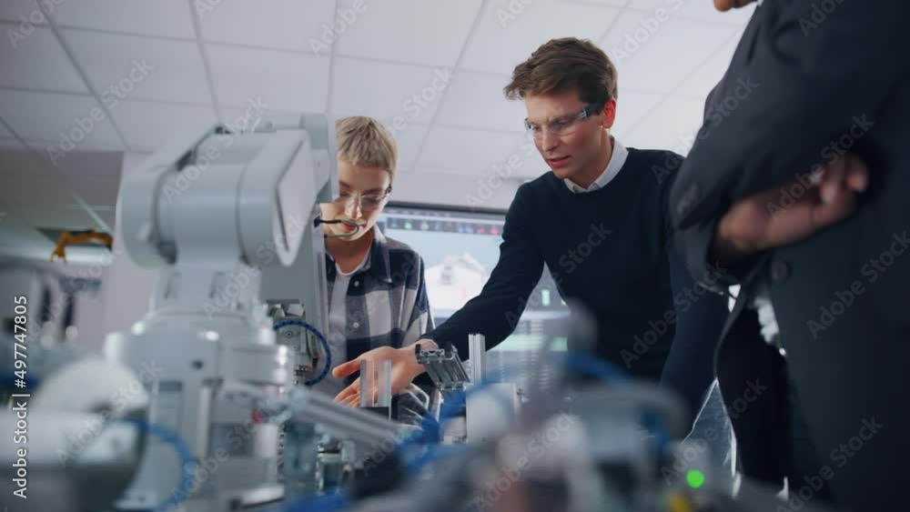 Aufkleber Serious Student Explaining Ideas to his Classmate and Black Teacher Using Robot Arm. Developers Programming Robotic Hand at University. Computer Science Education Concept. Low angle, slow motion