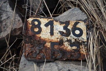 Rusty metal plates with numbers and letters on the stones