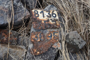 Rusty metal plates with numbers and letters on the stones