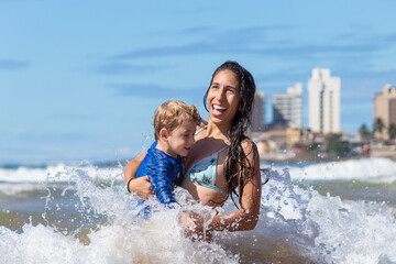 MÃE SORRINDO COM FILHO NA PRAIA. 