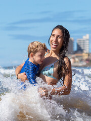 MÃE SORRINDO COM FILHO NA PRAIA. 