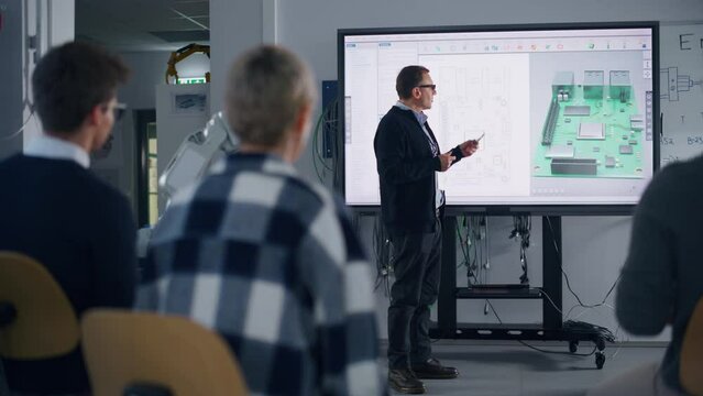 Diverse Team of Computer Design Students Talking at University with Teacher, Watching Interactive TV that shows 3D Concept Model of Printed Circuit Board. Education Concept