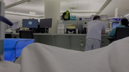 Medical bed with patient getting pushed through hospital corridors as back view of hospital staff are preparing researching profiles of admitted unwell people in a parts cut off no recognizable person