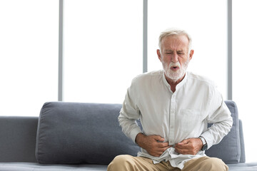 Fototapeta premium senior man have a stomachache and holding stomach on sofa