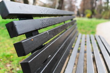 Close-up of a park bench with raindrops, selective focus