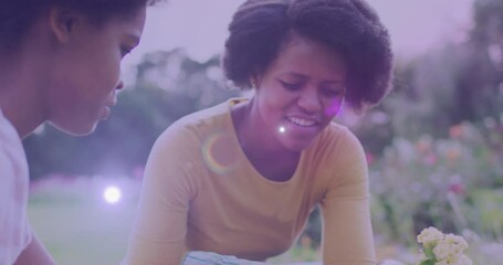 Spot of light against african american mother and daughter gardening together in the garden