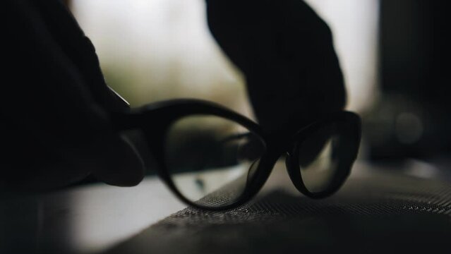 A man approaches the table and takes the glasses lying on the table in front of him. Shooting in close-up