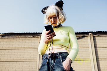 Young nonconformist woman outdoor using smartphone surfing 5g internet trading cryptocurrency