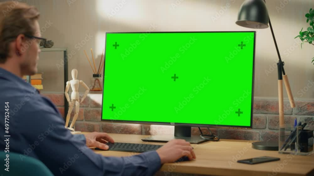 Aufkleber Young Handsome Man Working from Home on Desktop Computer with Green Screen Mock Up Display. Creative Male Checking Social Media, Browsing Internet. Living Room in Bright Loft Apartment. Arc Shot.