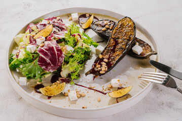 Vegetarian dish of grilled eggpland with vegetables, herbs and sauce