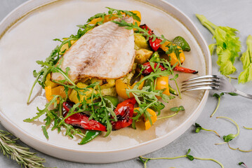 White fish dish with cherry tomatoes, lettuce, microgreens and sesame seeds
