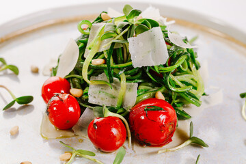 Salad of zucchini sliced ​​into strips, cherry tomatoes, parmesan cheese and microgreen. Vegan menu