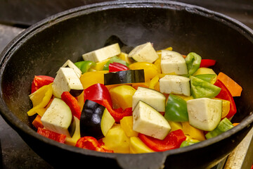 Carrots with potatoes and other vegetables are stewed on fire in a saucepan