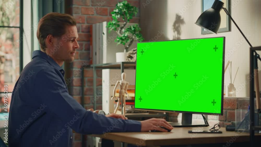 Poster young handsome man working from home on desktop computer with green screen mock up display. male che