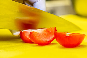 Cook cuts tomatoes on a yellow board