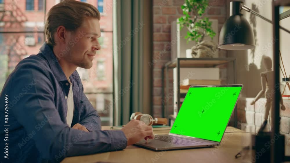Poster young handsome man working from home on laptop computer with green screen mock up display. creative 