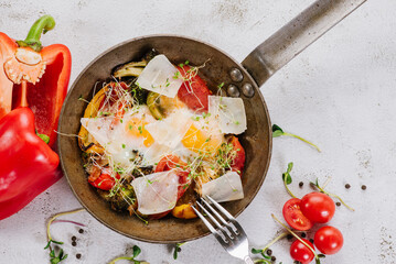 A pan with fried eggs with parmesan and vegetables