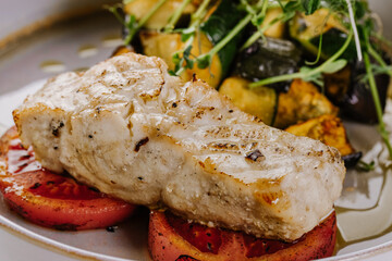 White fish dish with cherry tomatoes, lettuce, microgreens and sesame seeds