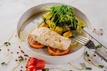 White fish dish with cherry tomatoes, lettuce, microgreens and sesame seeds