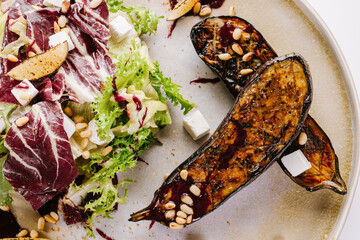 Vegetarian dish of grilled eggpland with vegetables, herbs and sauce