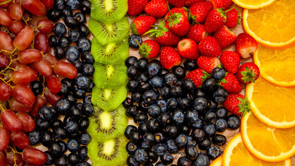 Fresh fruits concept, Arrangement of grapes kiwi orange and assorted berry as background