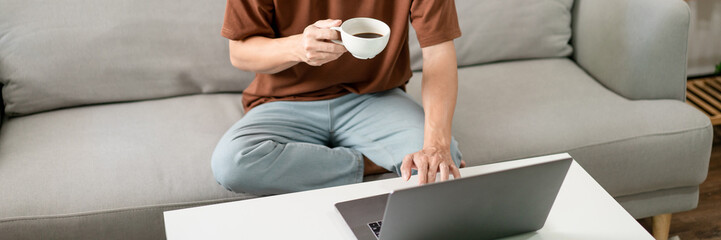 Technology Concept The man in brown T-shirt using one hand typing on his laptop while another hand...