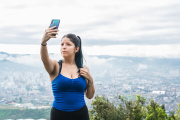 medium shot of young woman. latin influencer taking a selfie for her social networks on top of a...