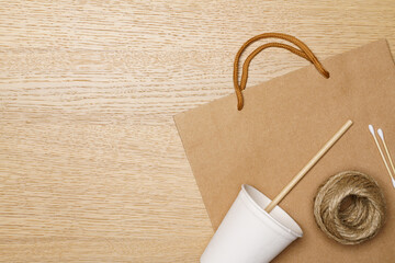 Eco friendly concept, Paper eco bag and jute rope with coffee cup and straws on wooden background