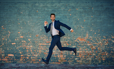 Eager to succeed. Portrait of a young corporate businessman jumping midair against a brick wall.