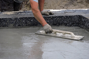 A building worker hand floating the wet concrete