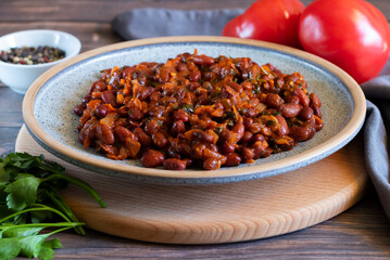 Lobio made of red beans on wooden cutting board with gray textiles, close-up