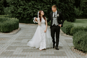 View of bride and groom walking in park