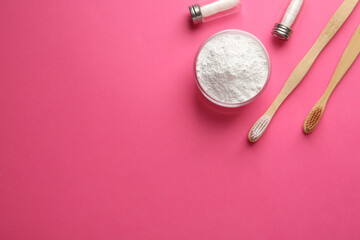 Bowl of tooth powder, brushes and dental flosses on pink background, flat lay. Space for text