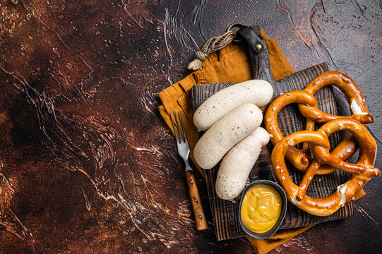 Traditional German pretzel with white sausage and mustard. Dark background. Top view. Copy space