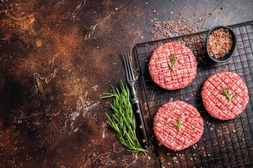 Raw burger cutlet from beef meat with spices and rosemary ready for cooking. Dark background. Top...