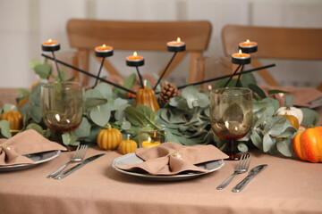 Fototapeta na wymiar Autumn table setting with eucalyptus branches and pumpkins indoors